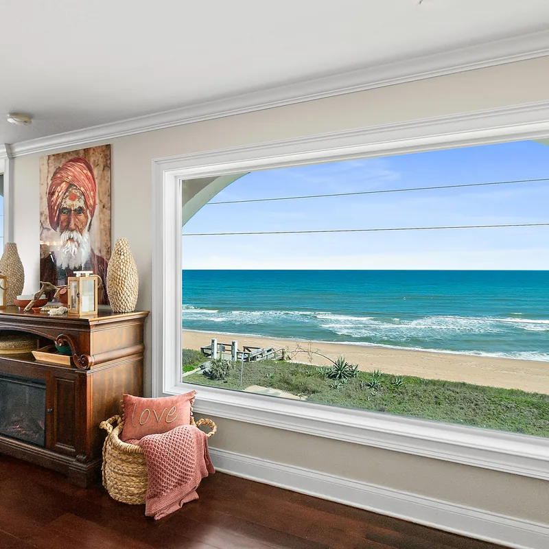 Wide picture window framing the Atlantic Ocean, dune line and beach from the penthouse living area