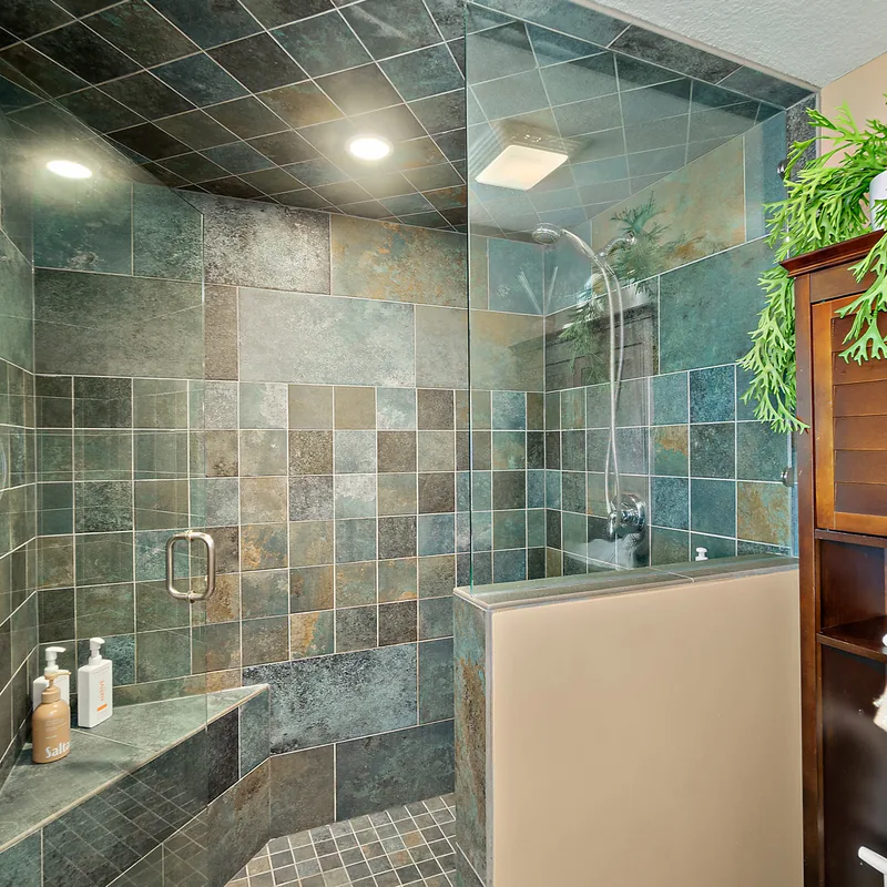 Walk-in slate tile shower with glass enclosure in the primary bathroom