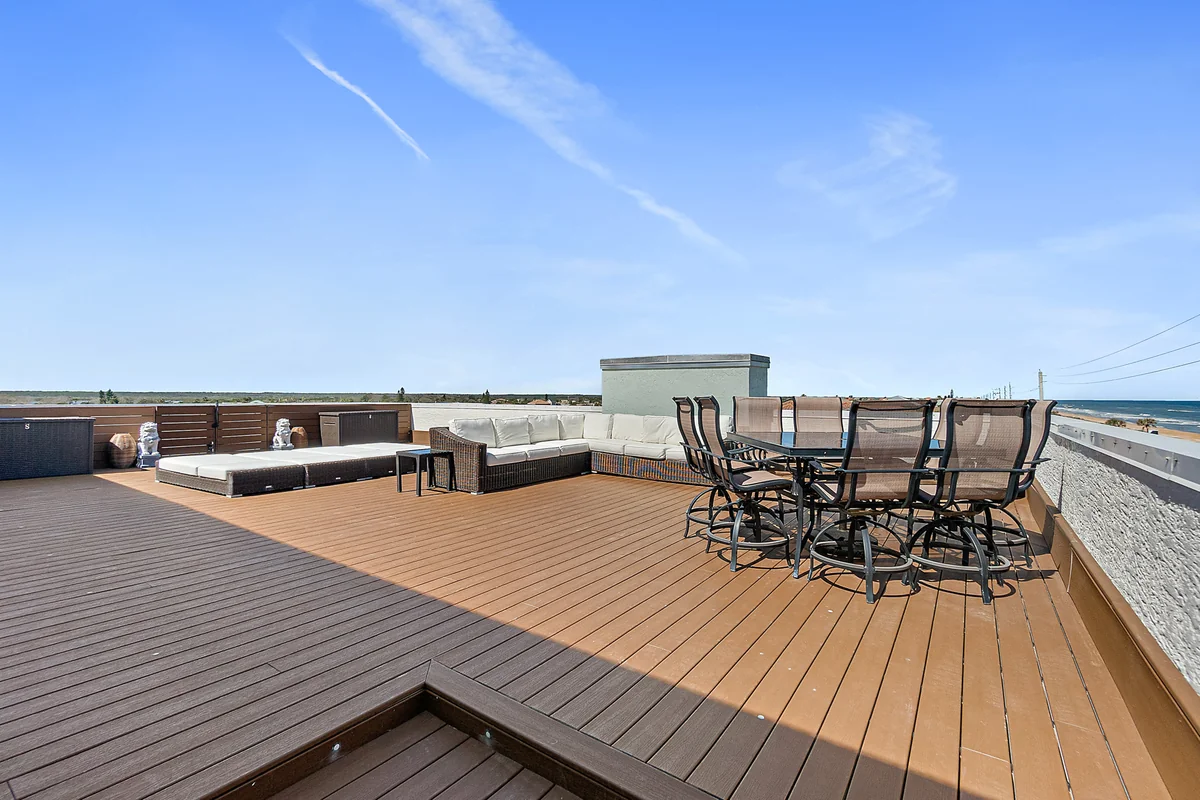 Private rooftop deck with lounge seating and outdoor dining set overlooking the Atlantic Ocean at 3390 Ocean Shore Blvd Unit 402
